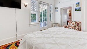 Un dormitorio con cama, televisor, ventilador de techo y ventana con persianas.