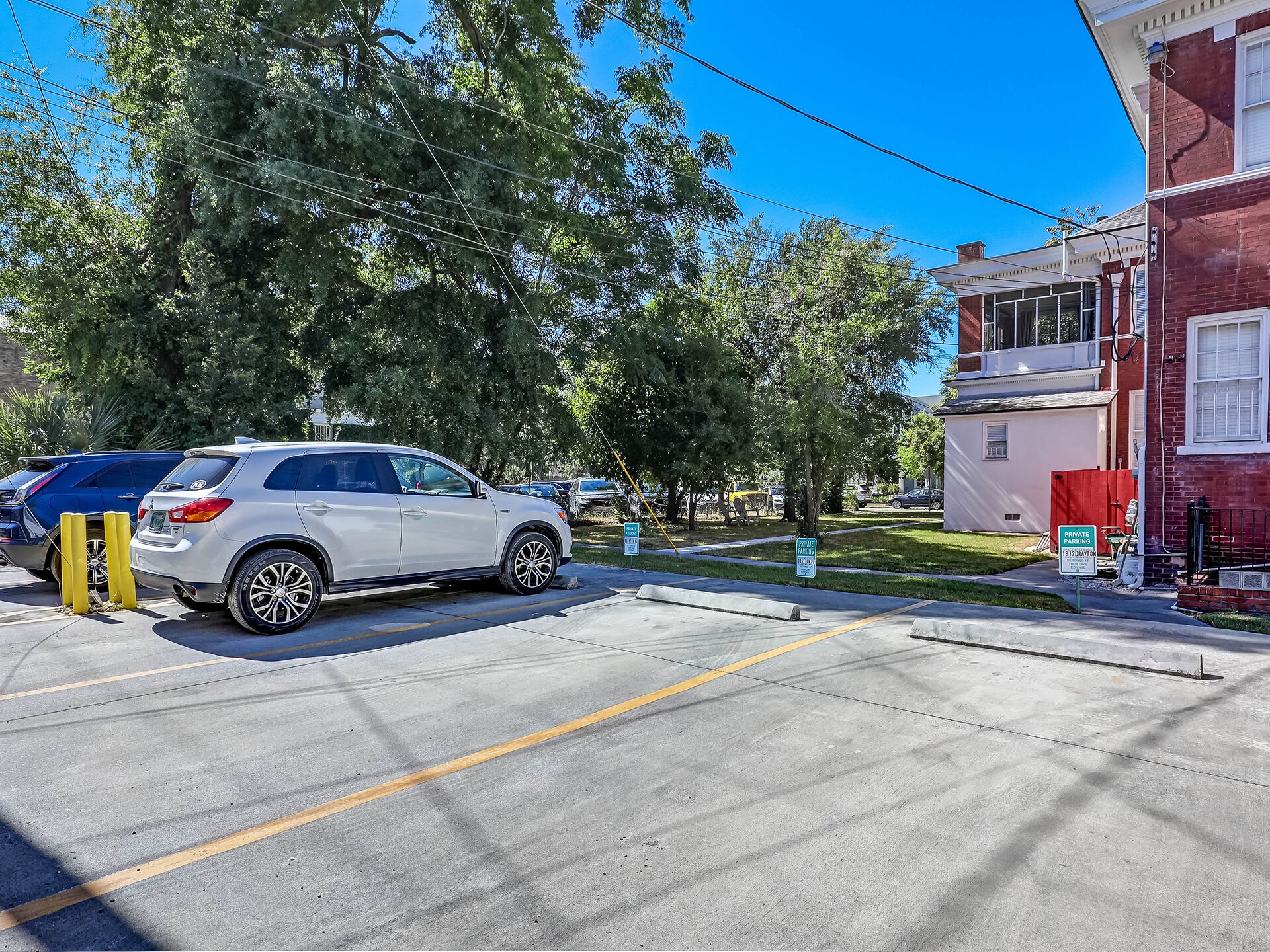 Un área de estacionamiento con una camioneta SUV blanca estacionada cerca de un edificio de fachada de ladrillo rojo.