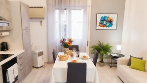 A modern living room with a dining area, a sofa, a coffee table, and a potted plant. - Apartment with A/C close to beaches | Ap26 (Imperia)