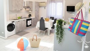 A compact kitchen with modern appliances, a dining area with a table and chairs, and a small living space with a TV and decorative items. - Apartment with A/C close to beaches | Ap26 (Imperia)