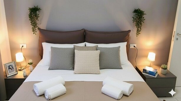 A neatly made bed with pillows and two rolled towels on the bed. - Apartment with A/C close to beaches | Ap26 (Imperia)