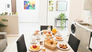 A modern kitchen with a dining table set for breakfast, featuring various foods and drinks. - Apartment with A/C close to beaches | Ap26 (Imperia)