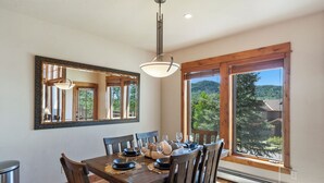 Un comedor con mesa de madera, sillas y un espejo grande.