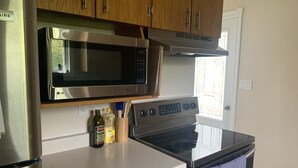 A kitchen with a stainless steel microwave, an oven, and wooden cabinets.