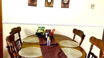 Ein Essbereich mit einem runden Tisch, vier Stühlen und einer Wand mit drei gerahmten Kunstwerken.