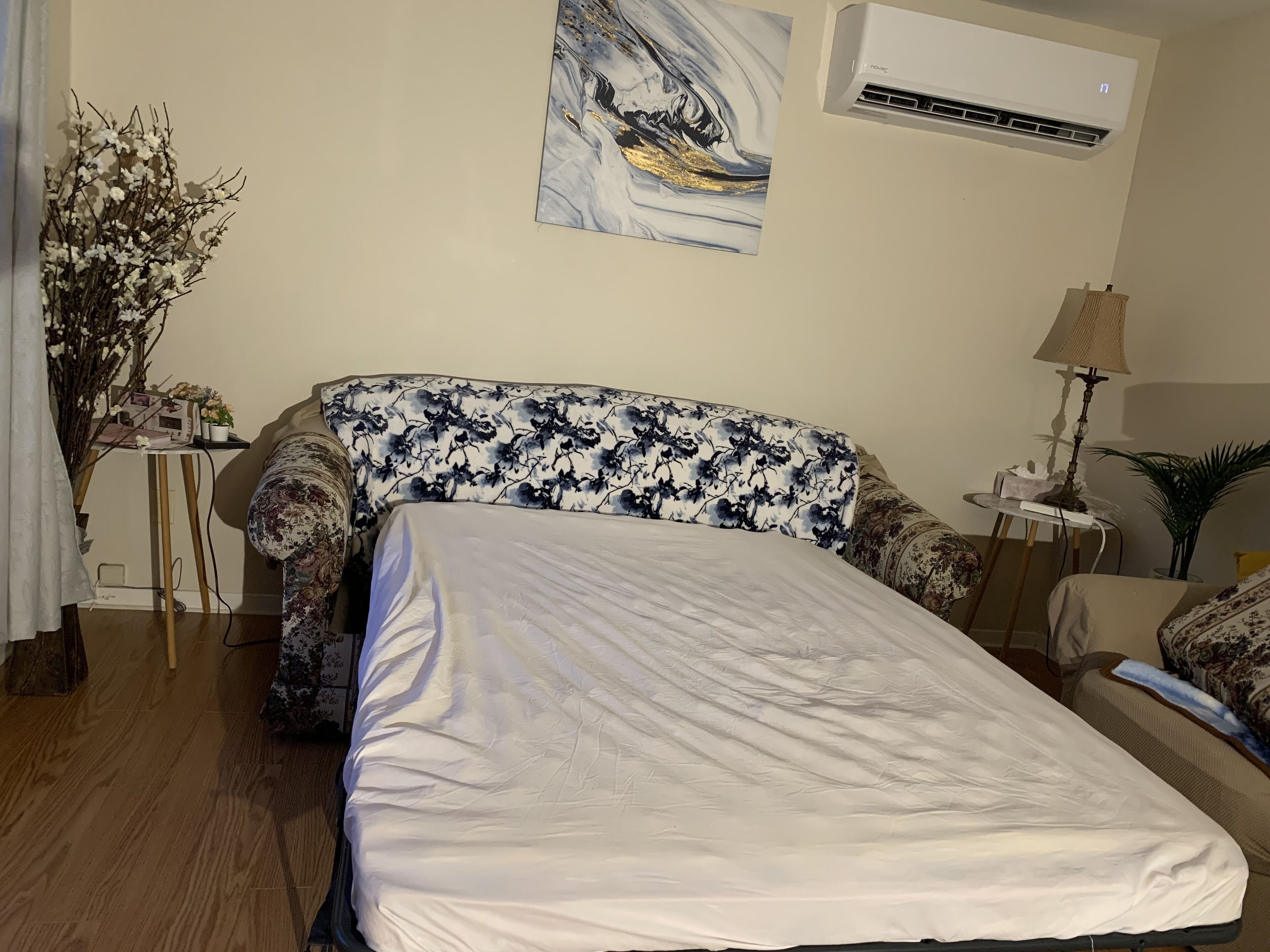Une chambre à coucher comprenant un lit, un bureau, une lampe et un climatiseur fixé au mur.