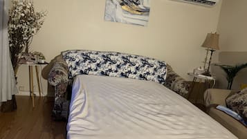 Une chambre à coucher comprenant un lit, un bureau, une lampe et un climatiseur fixé au mur.