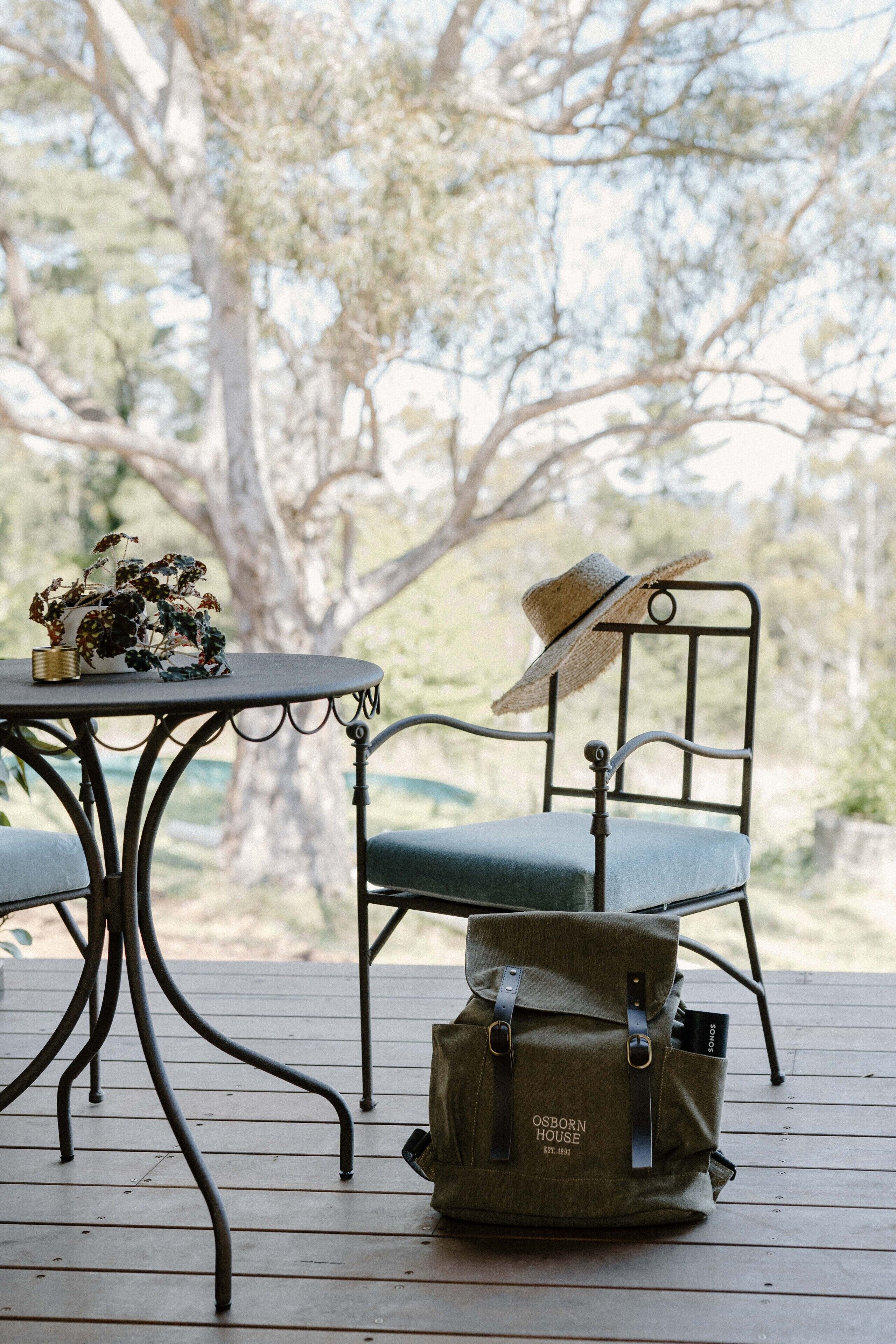A wooden deck with a metal table and chair, a wicker hat, and a bag labeled "OSBORN HOUSE."