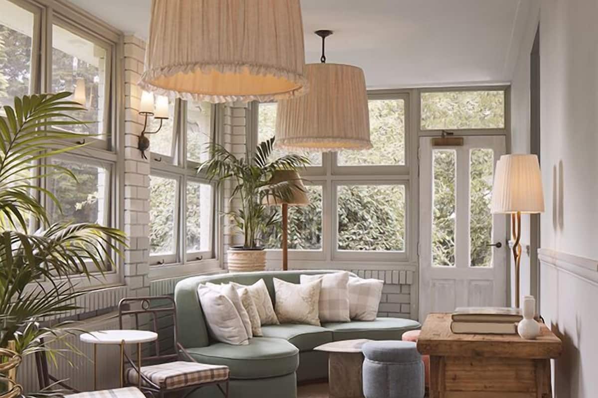 A cozy living room with a green sofa, two pendant lights, and a wooden table.