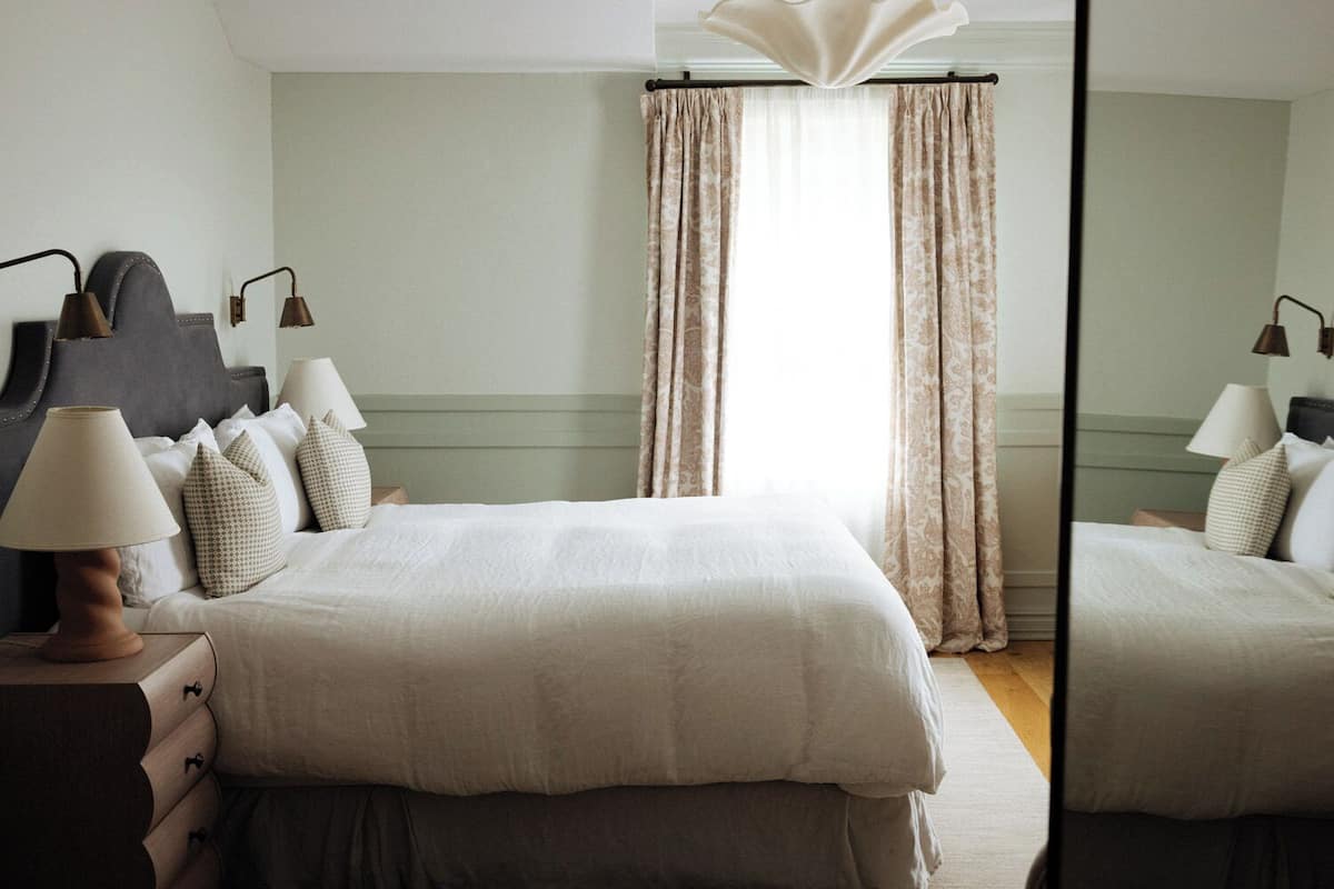 A neatly arranged bedroom with a large bed, two bedside tables with lamps, and a mirror.