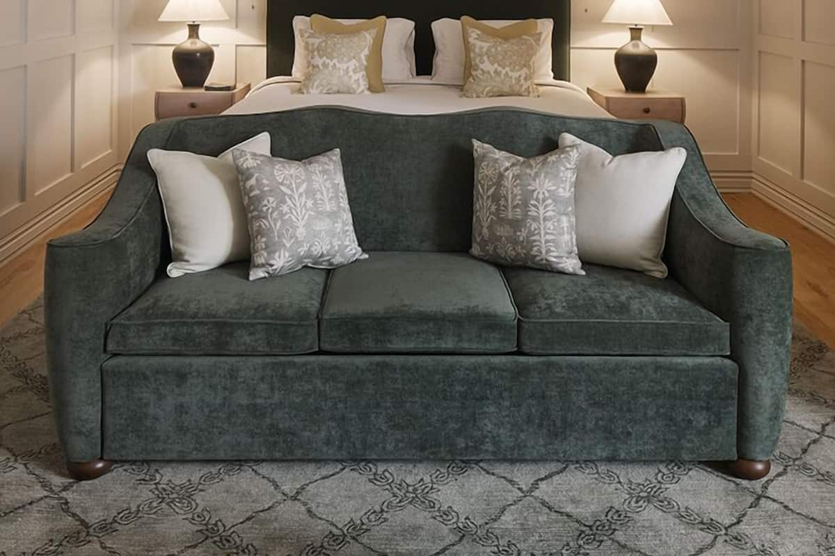 A bedroom with a large bed, two bedside tables, a green sofa, and a hanging light fixture.