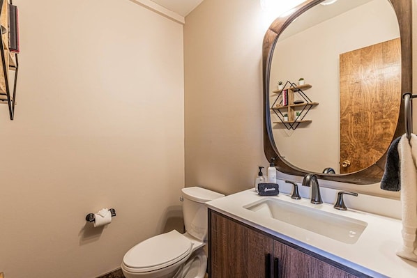 A bathroom with a white toilet, a sink with a mirror, and a towel rack.