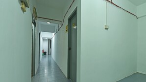 Un couloir avec un sol carrelé, une porte sur la droite et un panneau sur le mur.