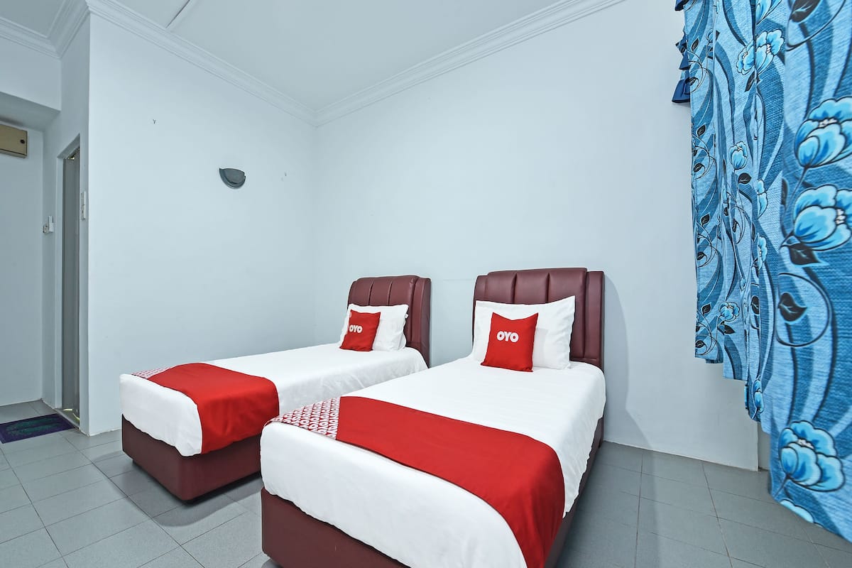 Ein Hotelzimmer mit zwei Betten, jeweils mit roter und weißer Bettwäsche und passenden Kissen.
