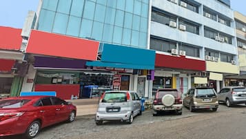A parking lot with several cars, a building with a blue glass facade, and a hotel with a red and blue awning.