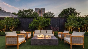 Eine Terrasse mit Feuerstelle, Gartenmöbeln und einem Holzzaun.
