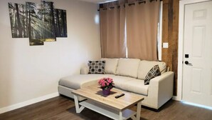 A living room with a sofa, a coffee table with a flower vase, and three wall-mounted paintings.