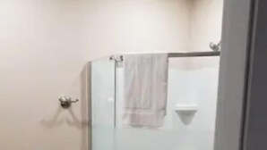 A bathroom with a glass shower enclosure, a white sink, and a toilet.
