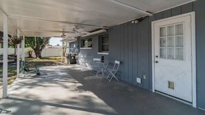A covered porch with a door, a small table, and two chairs. - Town 'n' Country Cozy Corner: Your Florida Fun Hub (Tampa)