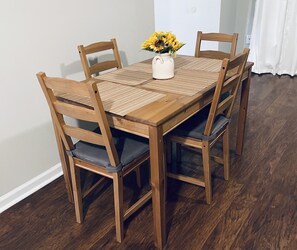 A wooden dining table with four chairs, a vase with yellow flowers, and a woven placemat. - Entire Home in Conyers (Conyers)
