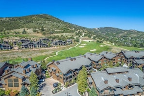 Ein Wohngebiet mit mehreren zweistöckigen Häusern, einem Golfplatz und einer hügeligen Landschaft im Hintergrund.