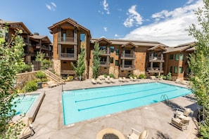 A multi-story hotel with a central swimming pool, outdoor seating, and balconies. - Juniper Landing (Park City)