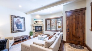 A spacious living room with a fireplace, a large sofa, a coffee table, and a stone fireplace surround.
