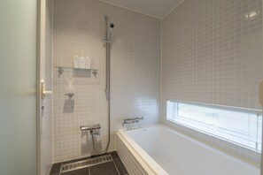 A modern bathroom with a bathtub, shower, and tiled walls. - Fo Sho Sansou (Kutchan)