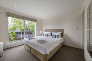 A modern bedroom with a large bed, a bedside table, and a window with a view of greenery outside. - Fo Sho Sansou (Kutchan)