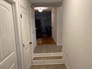 Staircase leads to an upper level from this well-lit hallway with doors on either side.