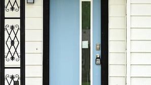 A house with a blue door, a black metal gate, and a small porch with steps. - Fully remodeled Cozy house, 10 min. from airport (Irving)