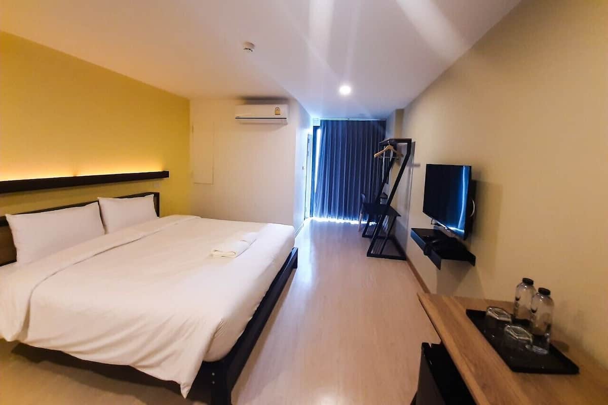 Habitación de hotel con cama, televisión, aire acondicionado y escritorio con mesita.