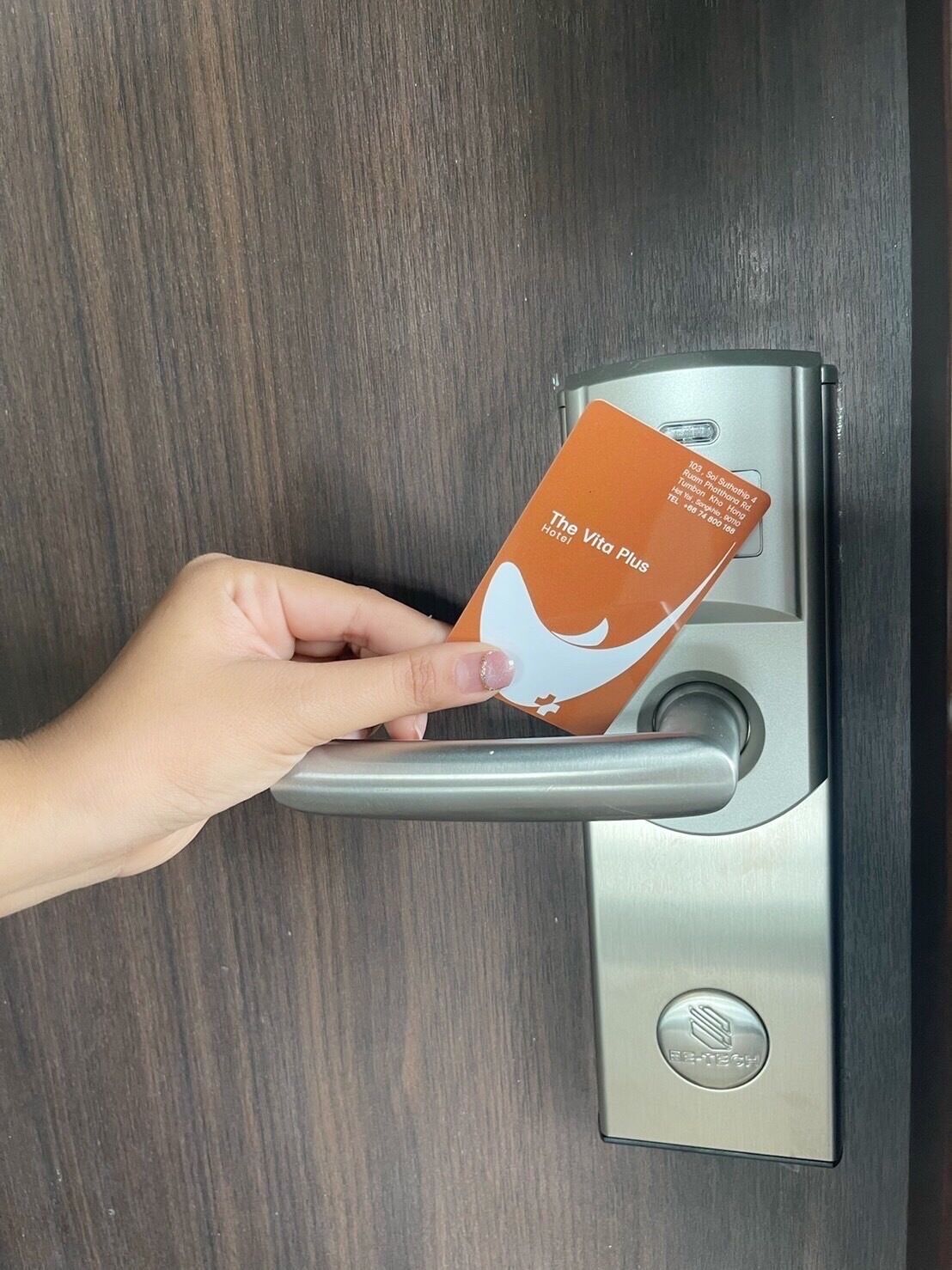 Una mano introduciendo una tarjeta de hotel en la cerradura de una puerta.