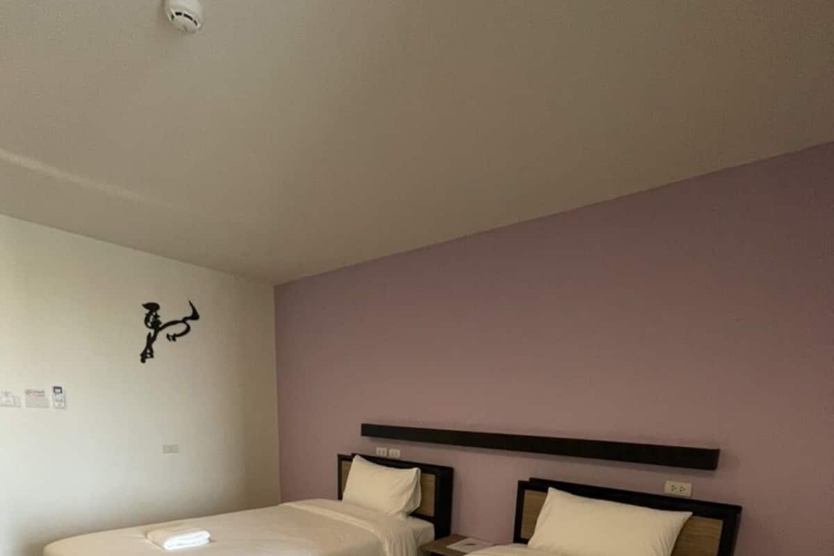 Habitación de hotel con dos camas, cada una con estructura de madera y ropa de cama blanca.