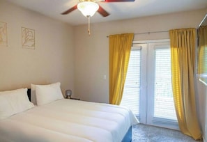 Relax in a serene space with a large bed, ceiling fan, and window with blinds.