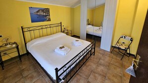 Ein Schlafzimmer mit einem Bett, einem Nachttisch, einem Sessel, einem Spiegel und einem Bild an der Wand.