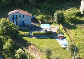 A stone building with a red roof, a small garden, and a water tank.