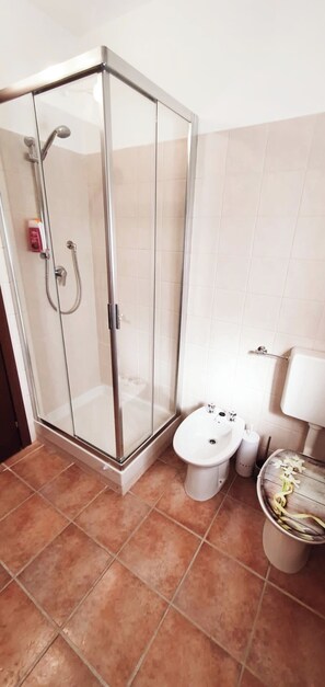 A bathroom with a glass-enclosed shower, a toilet, and a bidet.