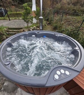A hot tub with water jets, surrounded by a wooden deck and greenery. - The Look of Nature (Framura)