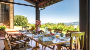 Mesa de café da manhã montada ao ar livre, com vista para o campo.