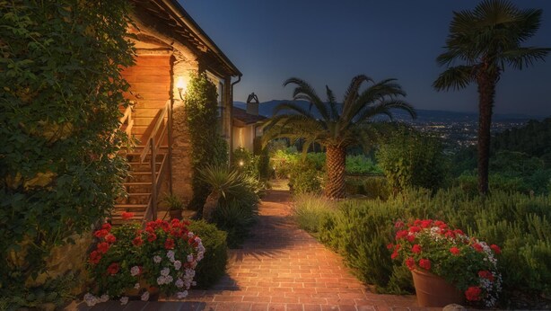 A stone pathway leading to a wooden house with a view of a cityscape at dusk. - Villa Marraccini 8 in Lucca (Lucca)