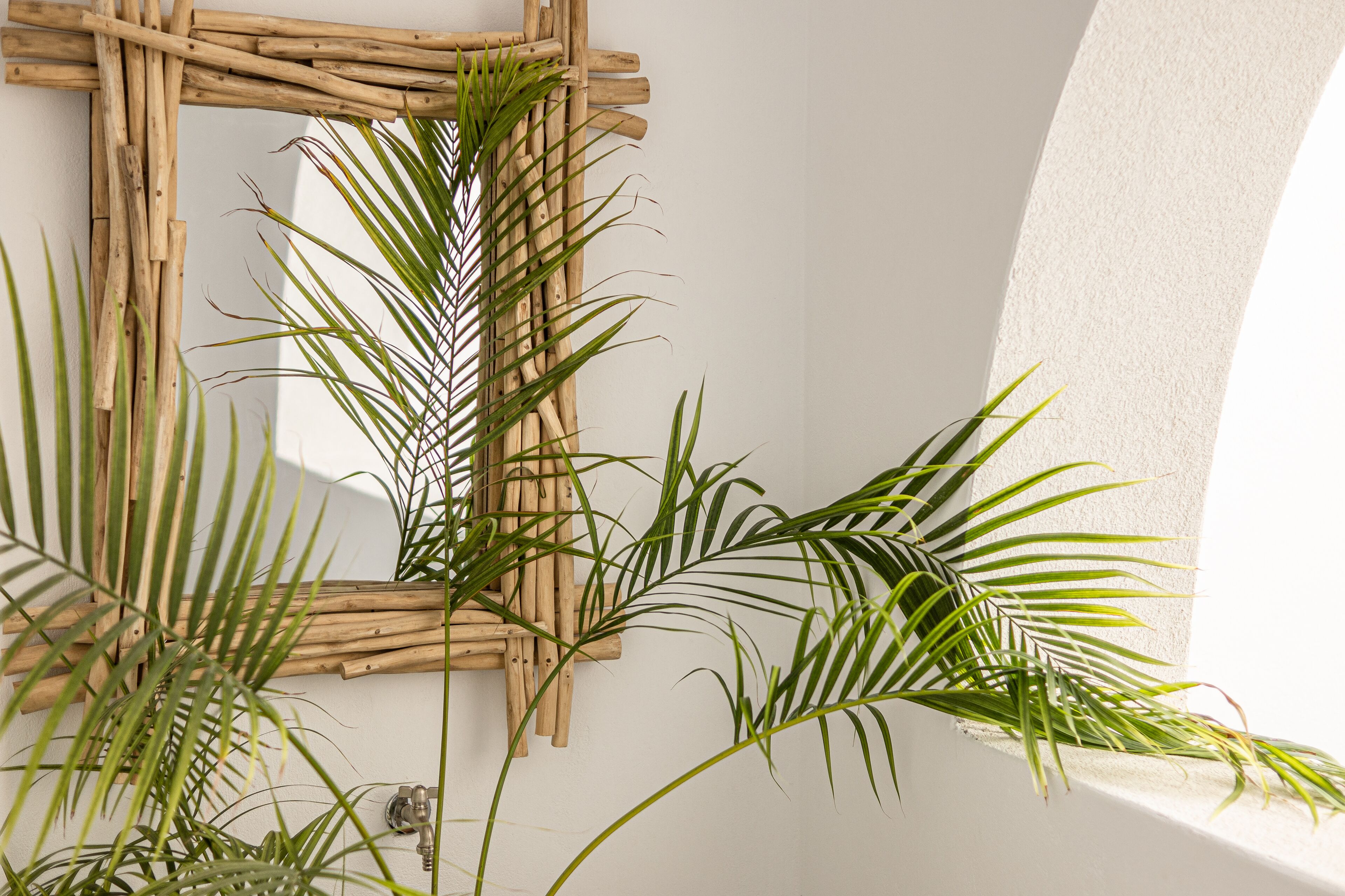 A wall with a woven wooden frame and green palm fronds.