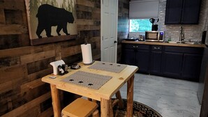 Une cuisine rustique aux murs en bois, une table à manger avec un set de table et un îlot central.