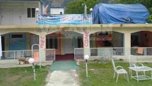 A two-story building with a covered outdoor seating area and a sign that reads "Hotel." - Frontier Hotel (Balakot)