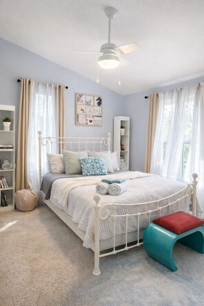 A bedroom with a bed, a ceiling fan, a window with curtains, a bookshelf, and a small stool. - 18-Acre Waterfront Sanctuary: Peace & Privacy (Ridge)