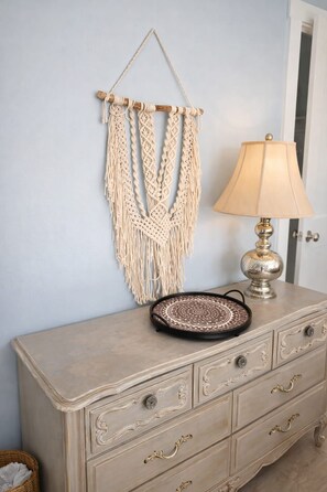 A beige dresser with ornate handles, a macrame wall hanging, and a patterned tray on top. - 18-Acre Waterfront Sanctuary: Peace & Privacy (Ridge)