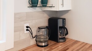 Eine Küche mit weißen Schränken, einer Kaffeemaschine und einer Kaffeekanne auf der Arbeitsfläche.