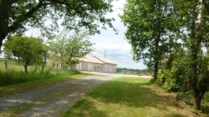 Una propietat rural amb un camí de grava que condueix a un edifici amb teulada de rajola.