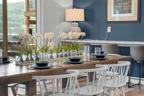 A dining table with white chairs, glass vases with white flowers, and blue dinnerware.