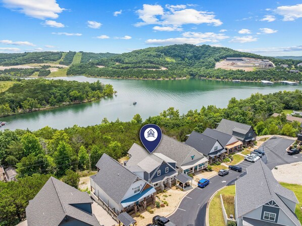 A residential area with houses, a lake, and a hilly landscape.